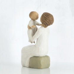 Close view of older figurine sitting on rock holding up baby