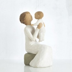 Close view of older figurine sitting on rock holding up baby