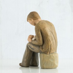 Boy sitting on rock holding a baby figurine