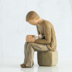 Boy sitting on rock holding a baby figurine