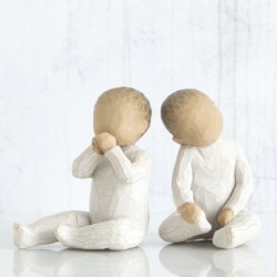 Two small baby figurines in all white onesies sitting down