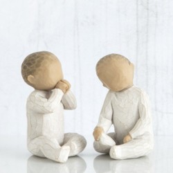 Two small baby figurines in all white onesies sitting down