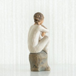 Faceless girl sitting on grey rock with arms holding baby