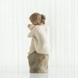 Faceless girl sitting on grey rock with arms holding baby
