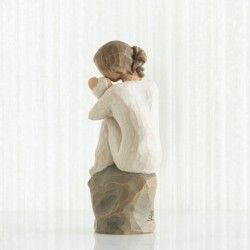 Faceless girl sitting on grey rock with arms holding baby