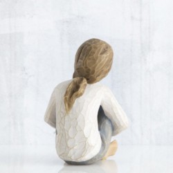 Small faceless figurine girl wearing white shirt and blue jeans with hands crossed on her legs