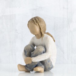 Small faceless figurine girl wearing white shirt and blue jeans with hands crossed on her legs