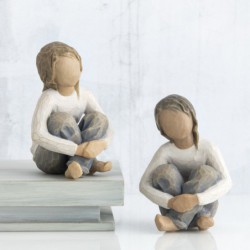 Small faceless figurine girl wearing white shirt and blue jeans with hands crossed on her legs