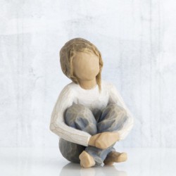 Small faceless figurine girl wearing white shirt and blue jeans with hands crossed on her legs