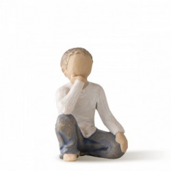 Small boy figurine in white shirt and blue jeans sitting down with one hand on his face