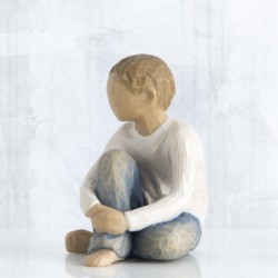 Faceless little boy sitting down wearing white shirt and jeans with hands over legs