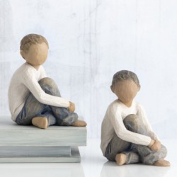 Faceless little boy sitting down wearing white shirt and jeans with hands over legs