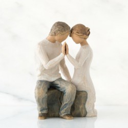 Faceless man and woman figurine sitting on rock wearing all white holding hands