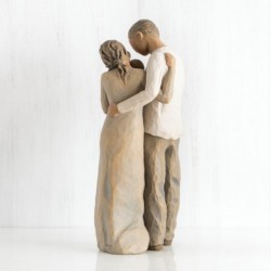 Mother and father figurines standing holding baby wrapped in white onesie