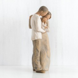 Mother and father figurines standing holding baby wrapped in white onesie