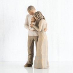 Mother and father figurines standing holding baby wrapped in white onesie