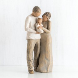 Mother and father figurines standing holding baby wrapped in white onesie