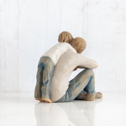 Father figurine sitting down hugging boy figurine from behind - both are wearing blue jeans and white shirts