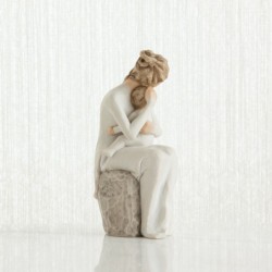 Mother figurine in white dress sitting down holding baby in her arms