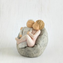 Young girl figurine sitting in light pink dress holding tiny baby in her arms - sitting on grey plush bean bag