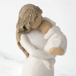 Front view of brunette woman figurine in white dress holding swaddled baby