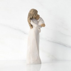 Front view of brunette woman figurine in white dress holding swaddled baby