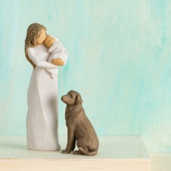 Front view of brunette woman figurine in white dress holding swaddled baby