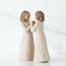 Two little girl figurines facing one another holding hands