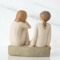 Two little girl figurines sitting on rocks looking at one another
