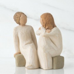 Two little girl figurines sitting on rocks looking at one another