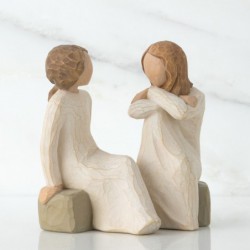 Two little girl figurines sitting on rocks looking at one another