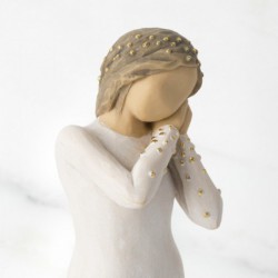 Front view of brunette girl figurine in white dress with gold dots holding her hands to her face