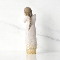 Front view of brunette girl figurine in white dress with gold dots holding her hands to her face