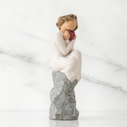 Faceless woman sitting on grey rock wearing all white holding pink heart