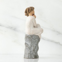 Faceless woman sitting on grey rock wearing all white holding pink heart