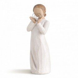 Angel figurine in white dress holding silver heart figurine up