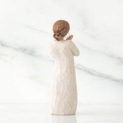 Angel figurine in white dress holding silver heart figurine up