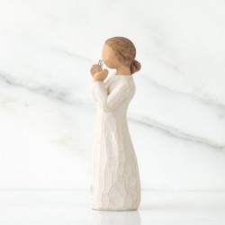 Angel figurine in white dress holding silver heart figurine up
