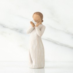 Angel figurine in white dress holding silver heart figurine up