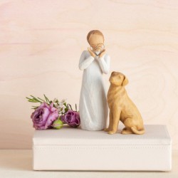 Angel figurine in white dress holding silver heart figurine up