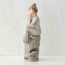Brunette woman figurine sitting on grey rock