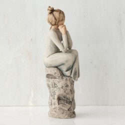Brunette woman figurine sitting on grey rock