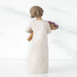 Girl figurine in white dress carrying purple flowers in arms