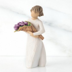 Girl figurine in white dress carrying purple flowers in arms