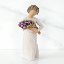 Girl figurine in white dress carrying purple flowers in arms