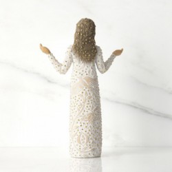 Front view of brunette girl figurine in white dress with gold dots holding her hands out