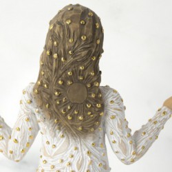 Front view of brunette girl figurine in white dress with gold dots holding her hands out