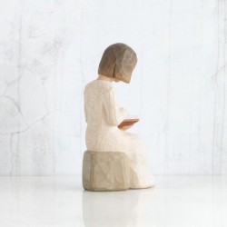 Little girl figurine sitting down reading a book