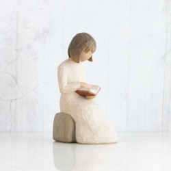 Little girl figurine sitting down reading a book