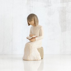 Little girl figurine sitting down reading a book